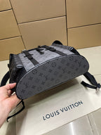 Backpack lying flat showing monogram print, webbed straps, and front buckles