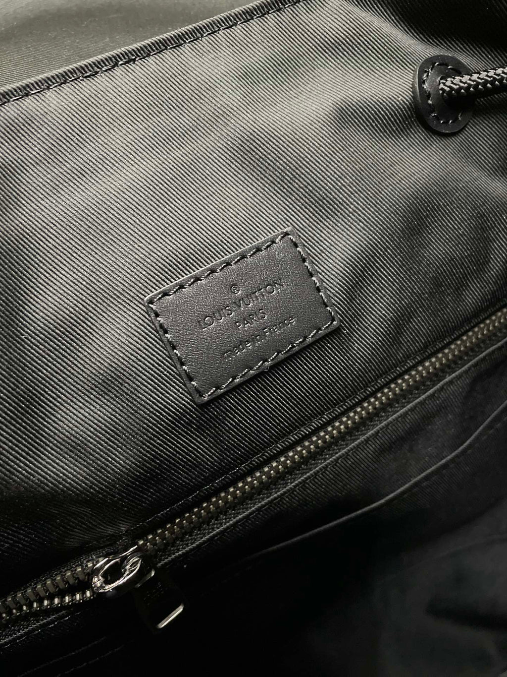 Backpack zipper pocket close-up with Louis Vuitton leather label and metal zipper