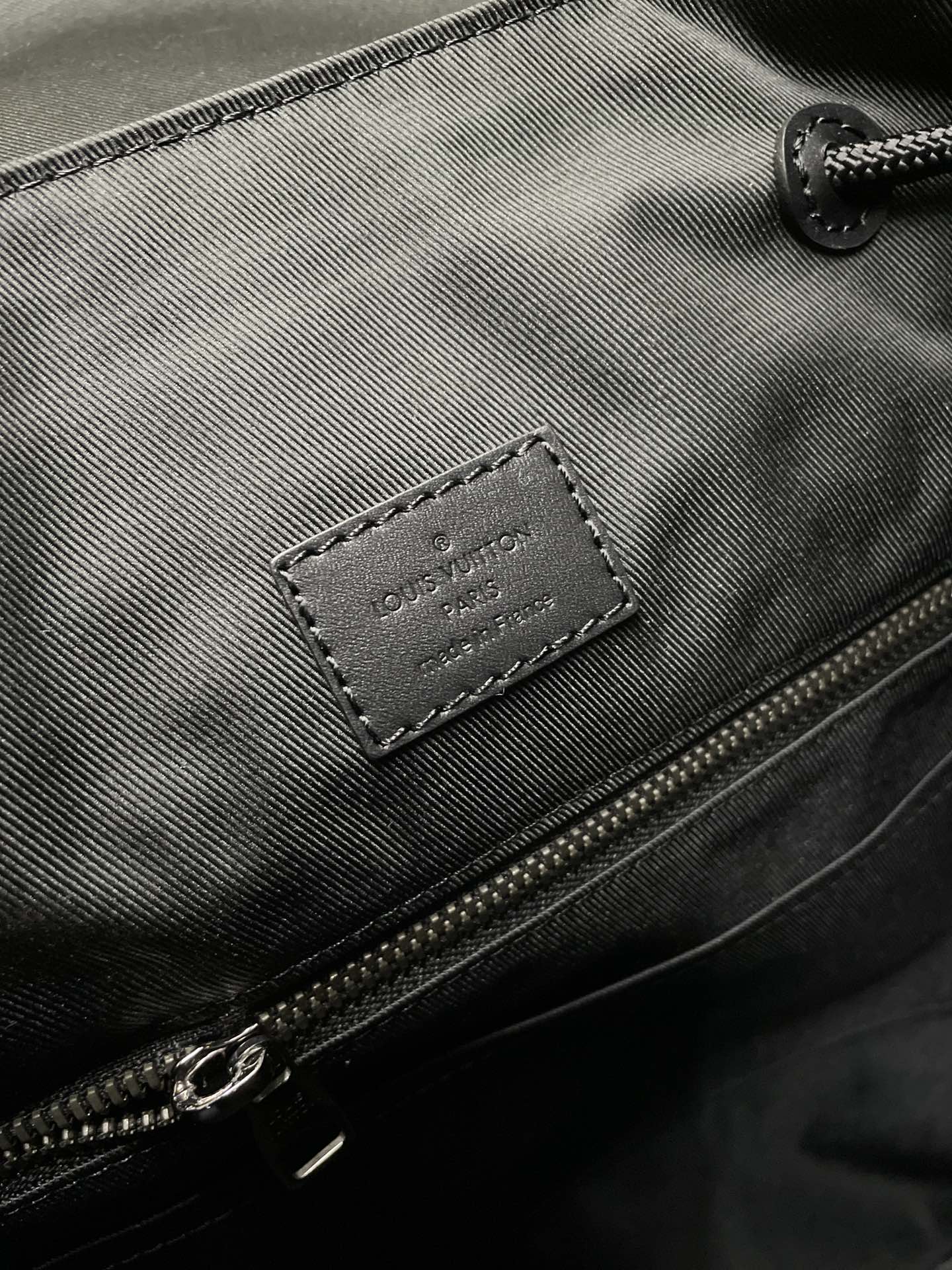 Backpack zipper pocket close-up with Louis Vuitton leather label and metal zipper