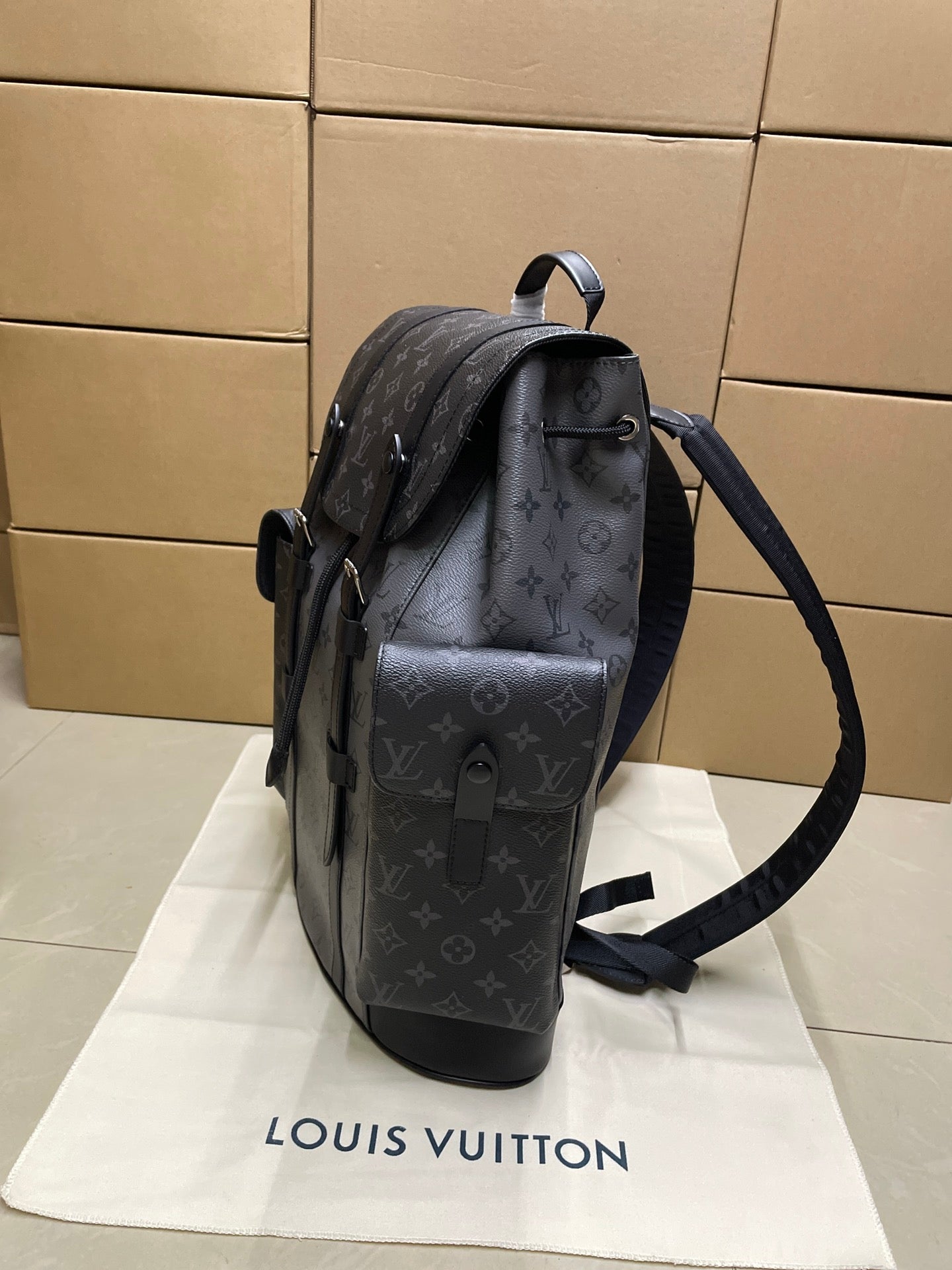 Monogram backpack side view with adjustable shoulder strap and top handle