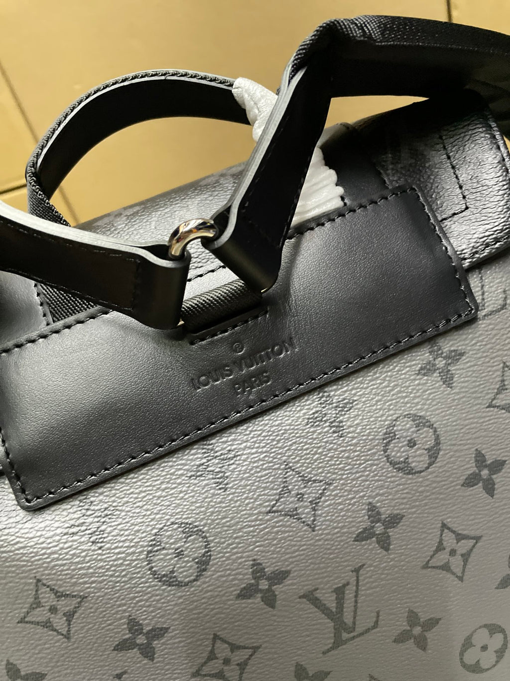 Backpack close-up of grained leather trim, metal ring, and monogram pattern