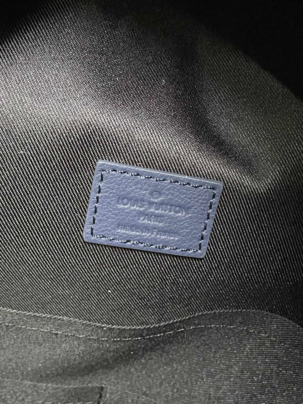 Louis Vuitton monogram backpack close-up of navy fabric label with stitched border