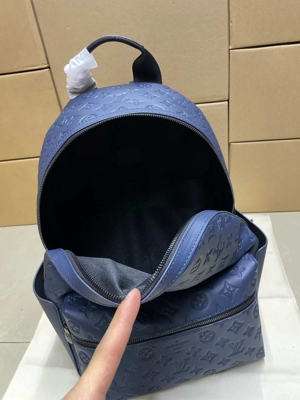 Louis Vuitton monogram backpack in navy blue, open top showing dark interior