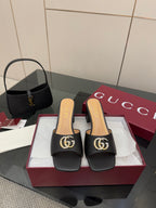 Black mule sandals with gold-tone GG buckle and low block heel
