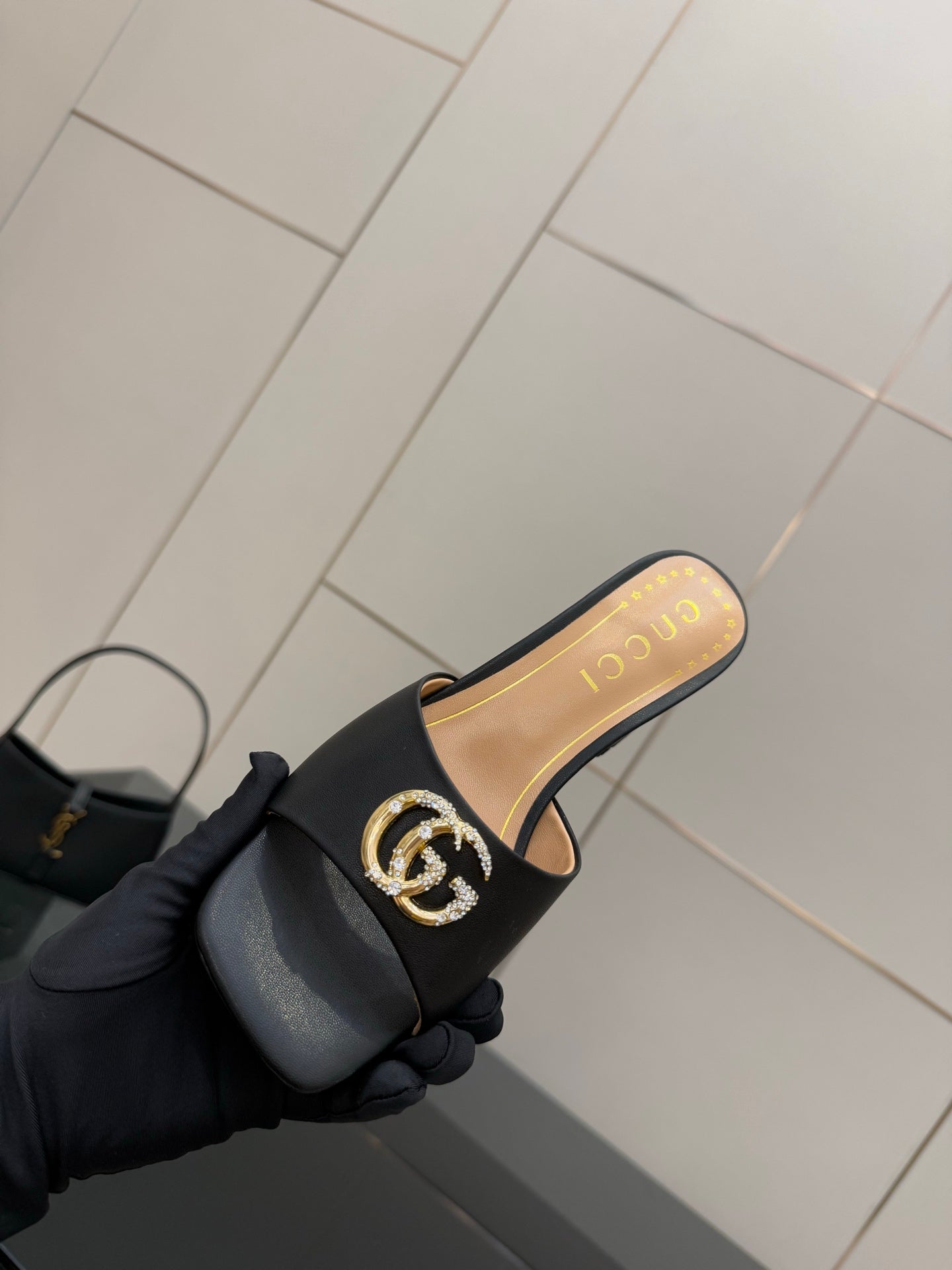 Black mule sandal with gold-tone GG buckle on black strap