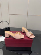 Women’s pink heeled slide sandals with gold logo detail on the front strap