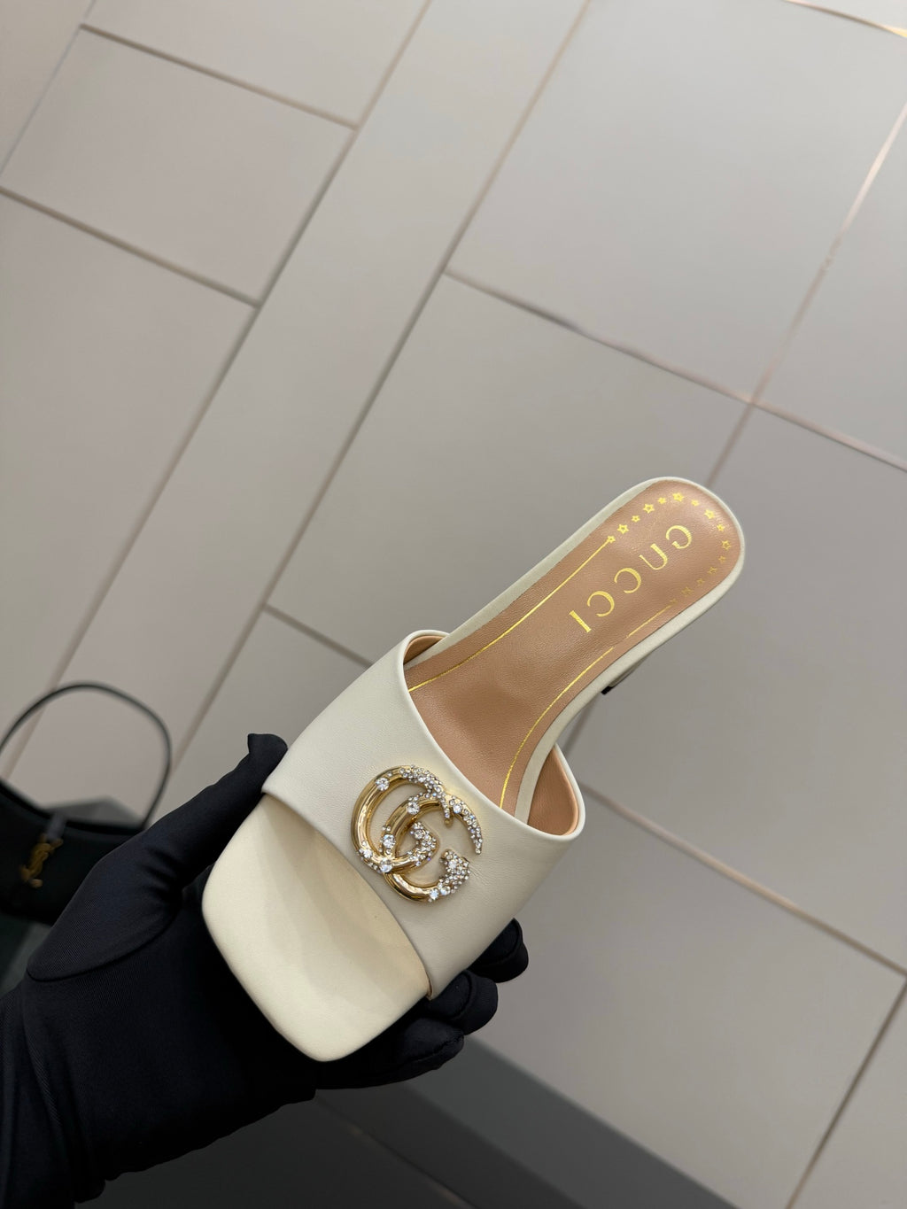 Gucci ladies cream mules with gold-tone logo buckle, angled top view