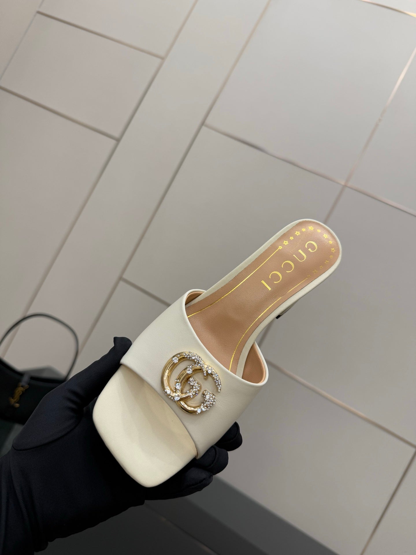 Gucci ladies cream mules with gold-tone logo buckle, angled top view
