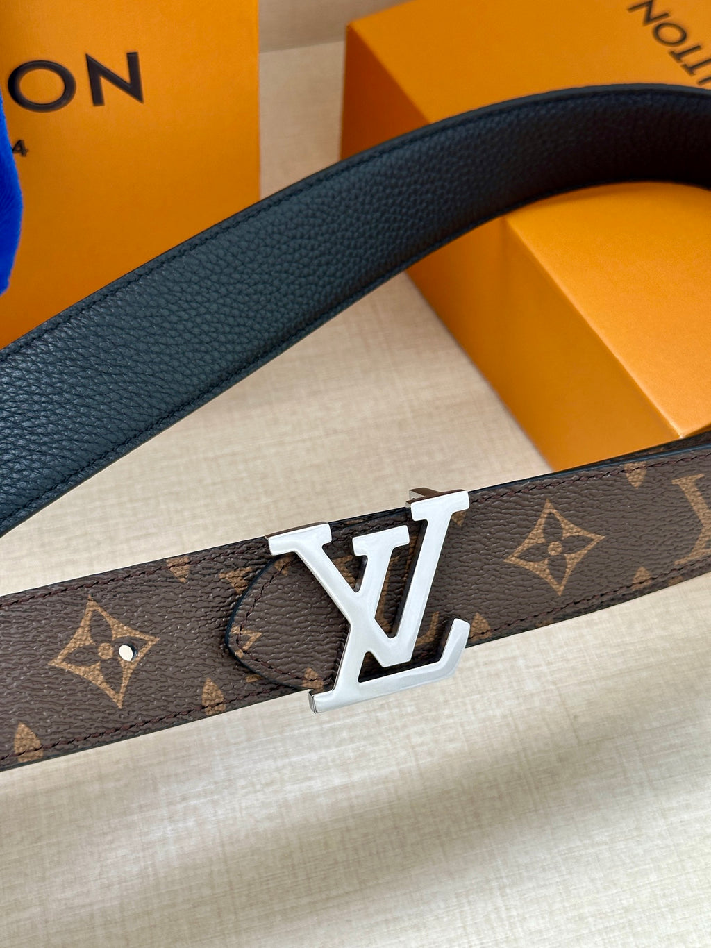 Dark monogram belt with gold-tone LV buckle close-up on textured strap