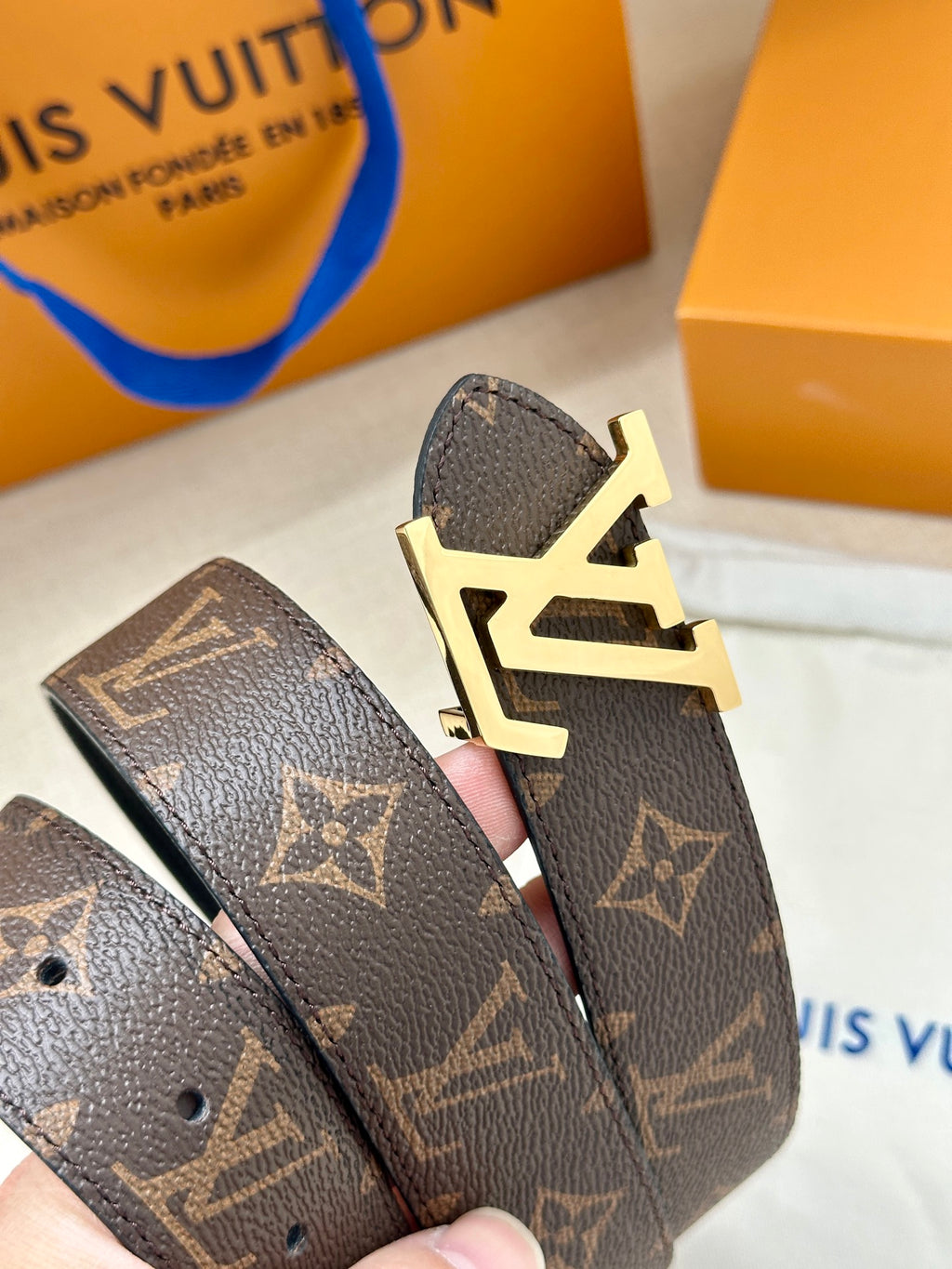 Gold-tone belt buckle detail with LV initials on brown monogram strap