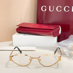 Gold round eyeglasses with clear lenses, GG-pattern temples, and black arms.