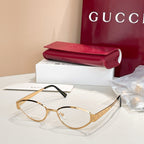 Gold round eyeglasses with clear lenses, GG-pattern temples, and black arms.