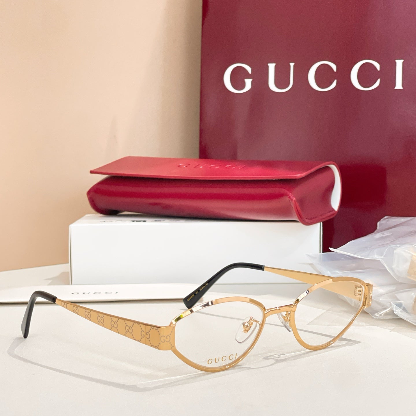 Gold round eyeglasses with clear lenses, GG-pattern temples, and black arms.