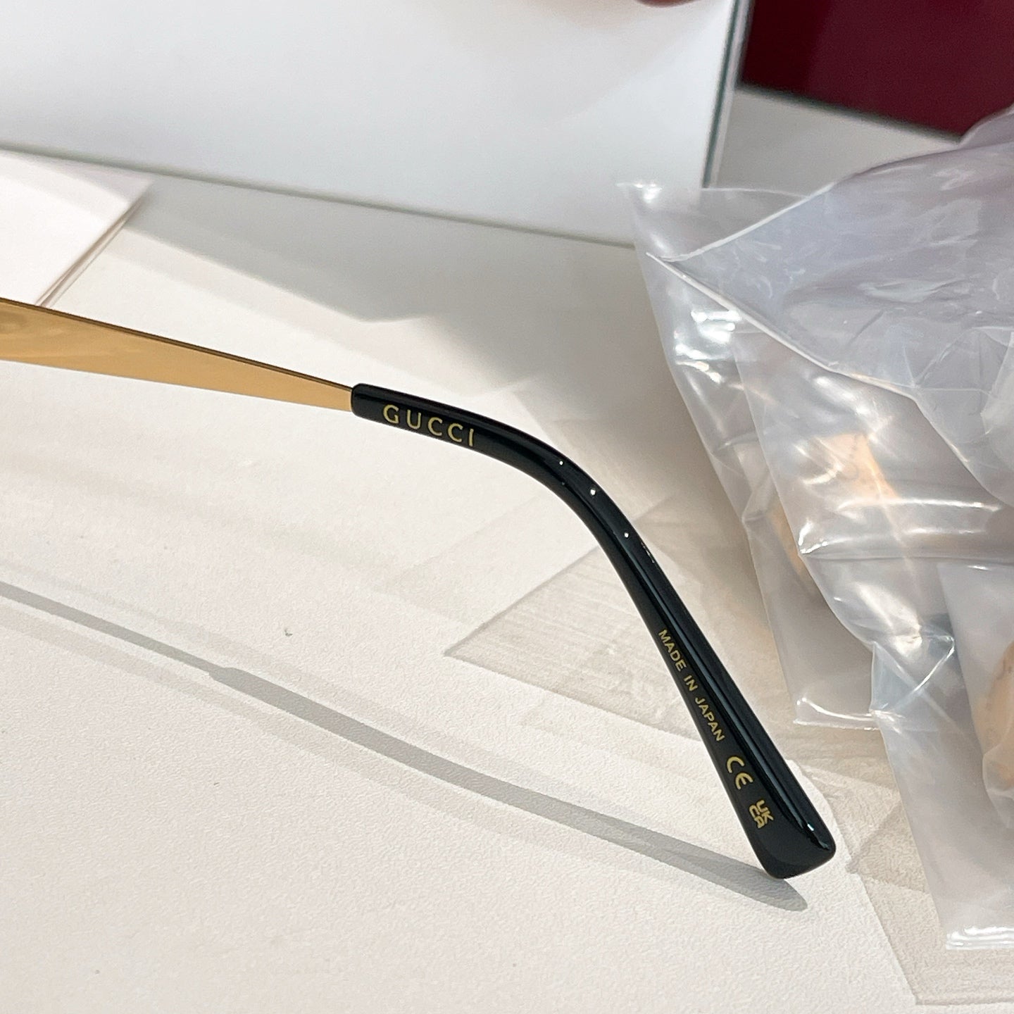 Black eyeglass temple arm with gold Gucci logo and CE marking.