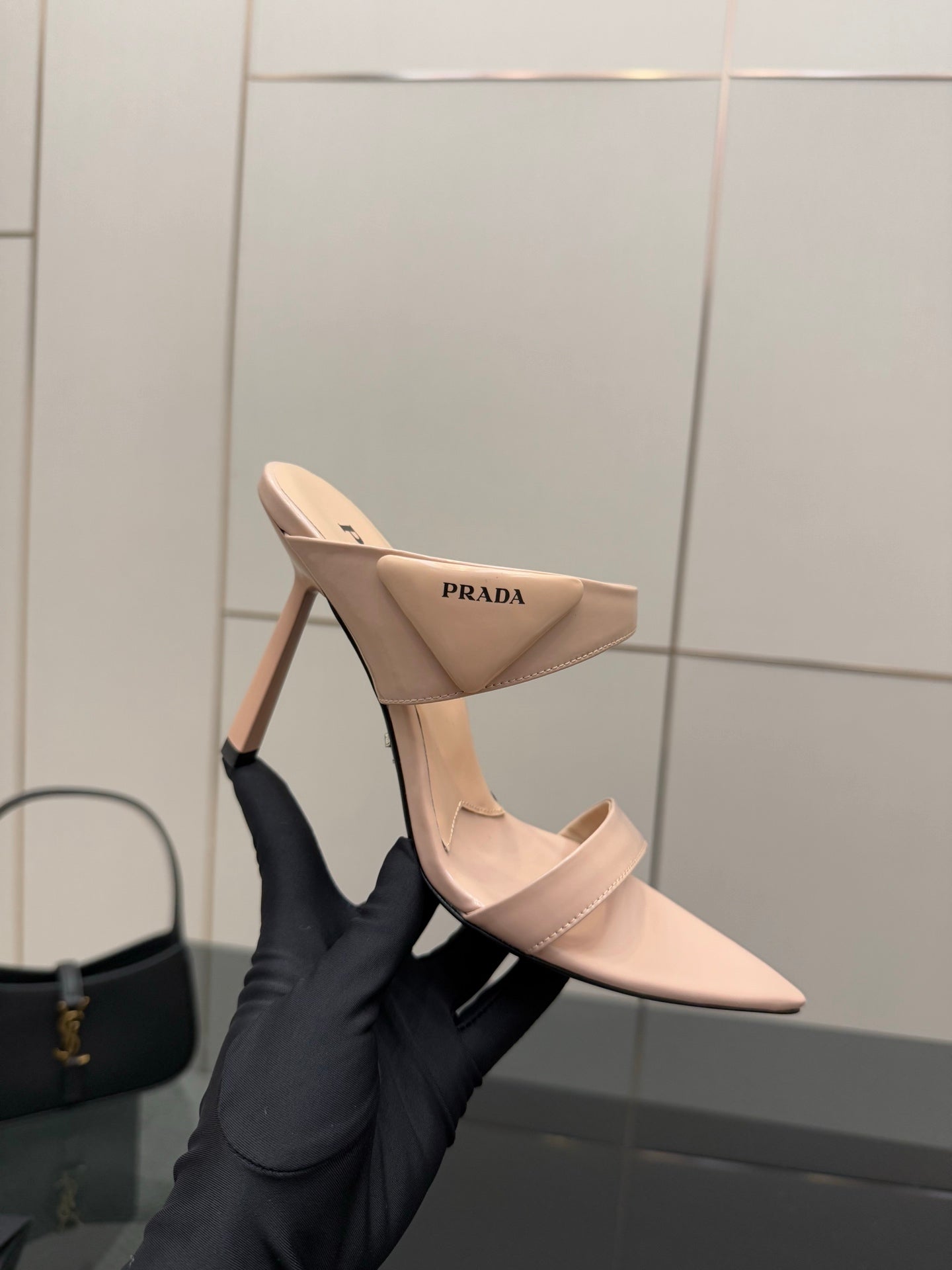 Prada women’s light beige mules with stiletto heel, back view in hand