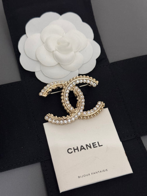 Gold-tone rhinestone Chanel brooch with oval C motif on cream card