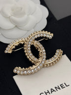 Gold-tone rhinestone Chanel brooch with oval C center and curved row details