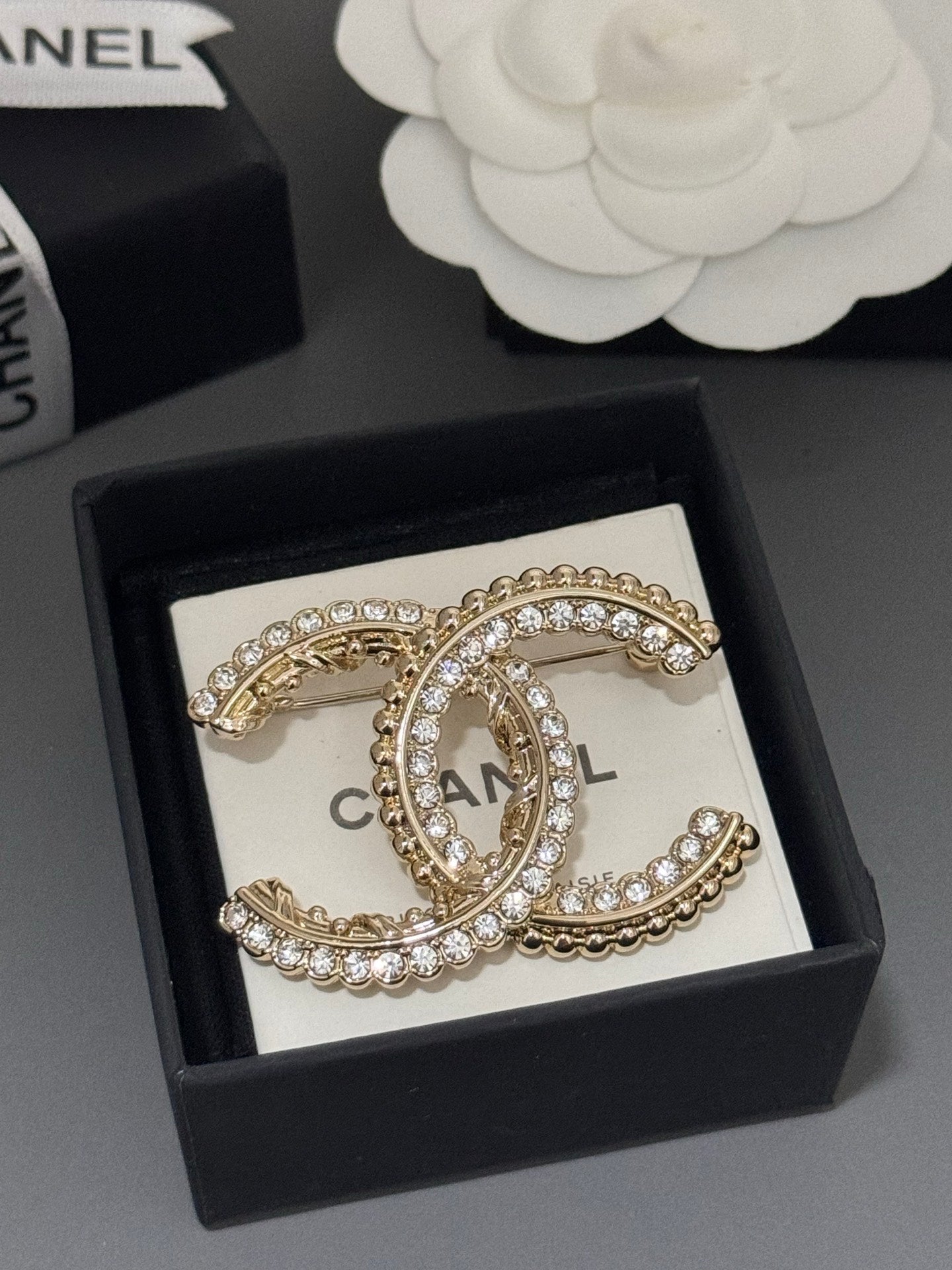 Gold-tone rhinestone Chanel brooch in black box with oval C centerpiece