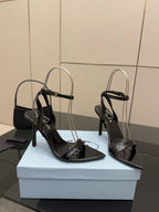 Pair of black high-heel sandals with thin ankle straps and glossy finish
