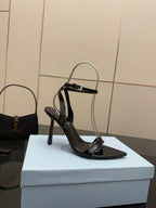 Black glossy high-heel sandal with ankle strap and sculpted stiletto heel