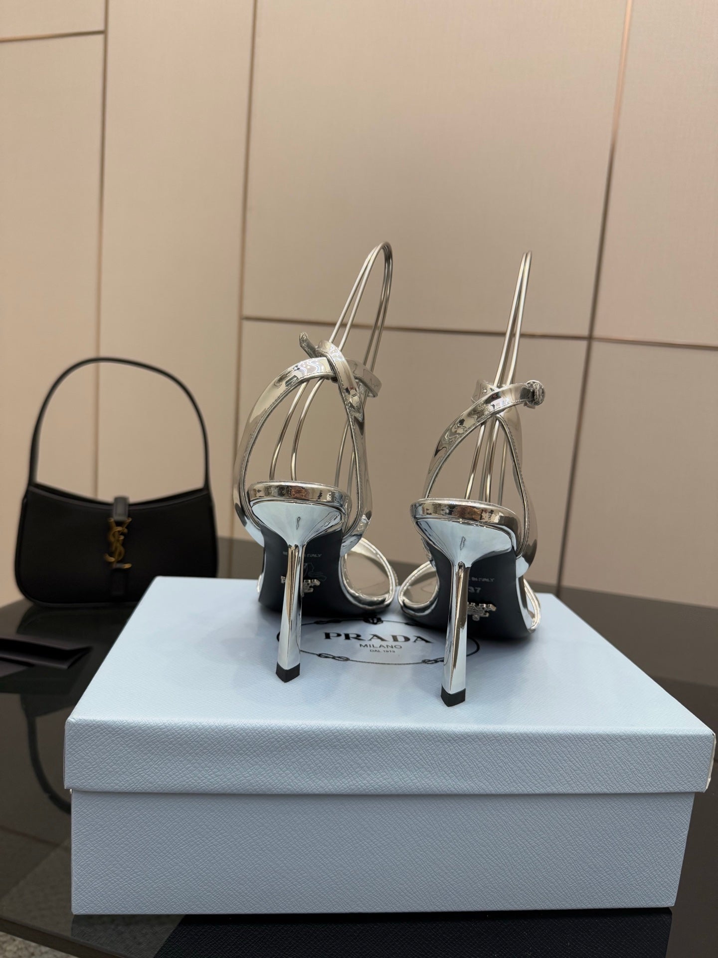 Prada women's metallic silver heeled sandals, back view with ankle straps