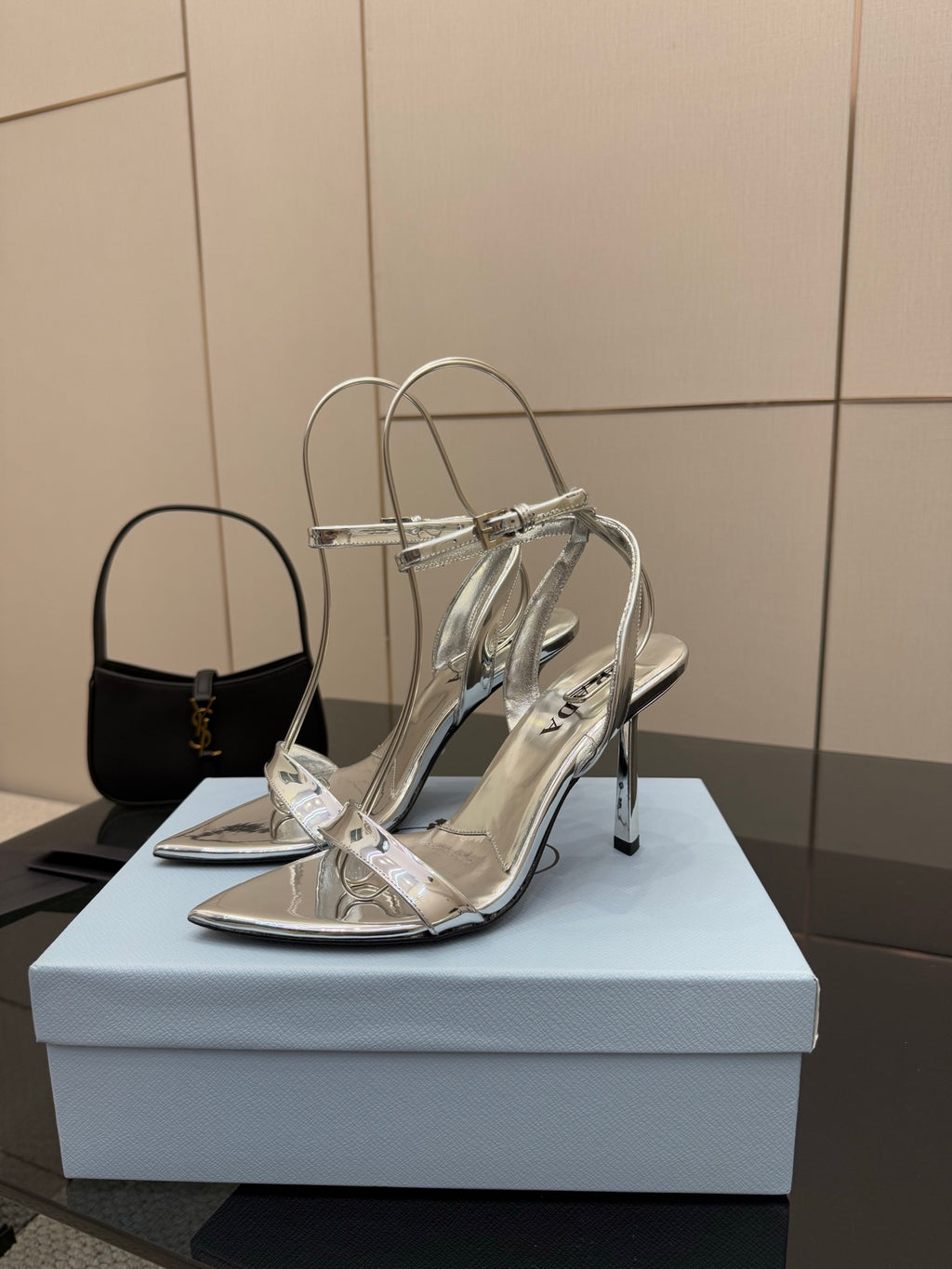 Prada women's metallic silver heeled sandals, front view on display stand