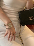 Gold-tone Chanel charm bracelets and cuff bracelets on a wrist