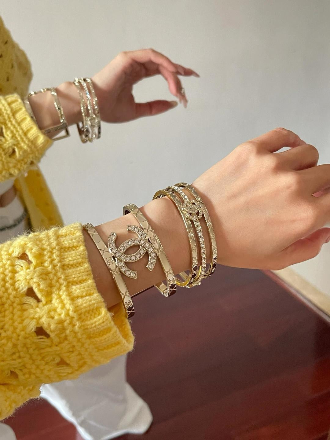 Gold-tone Chanel logo cuff bracelet with layered bangles on wrist