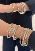 Gold-tone Chanel logo bangle bracelets with rhinestone accents