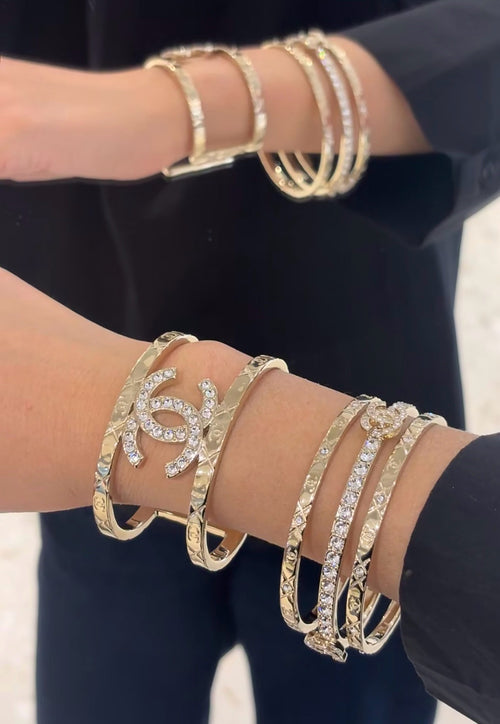 Gold-tone Chanel logo bangle bracelets with rhinestone accents