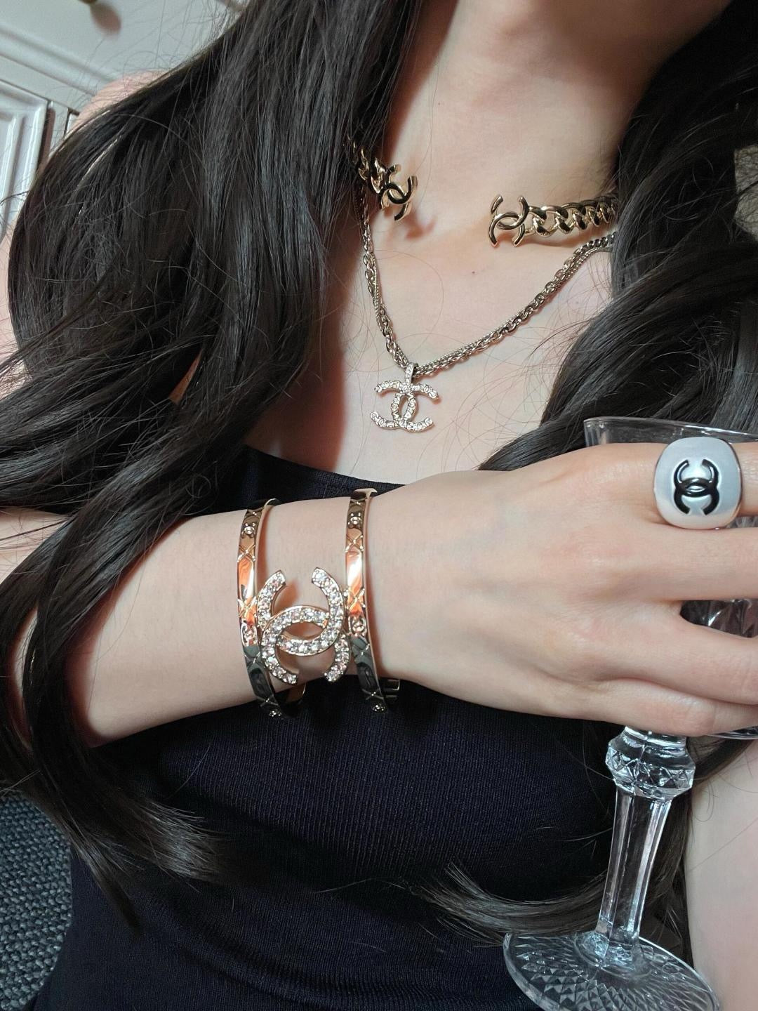 Gold-tone Chanel chain bracelet with rhinestone logo on the wrist