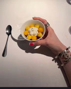 Silver-tone charm bracelets on hand holding a bowl