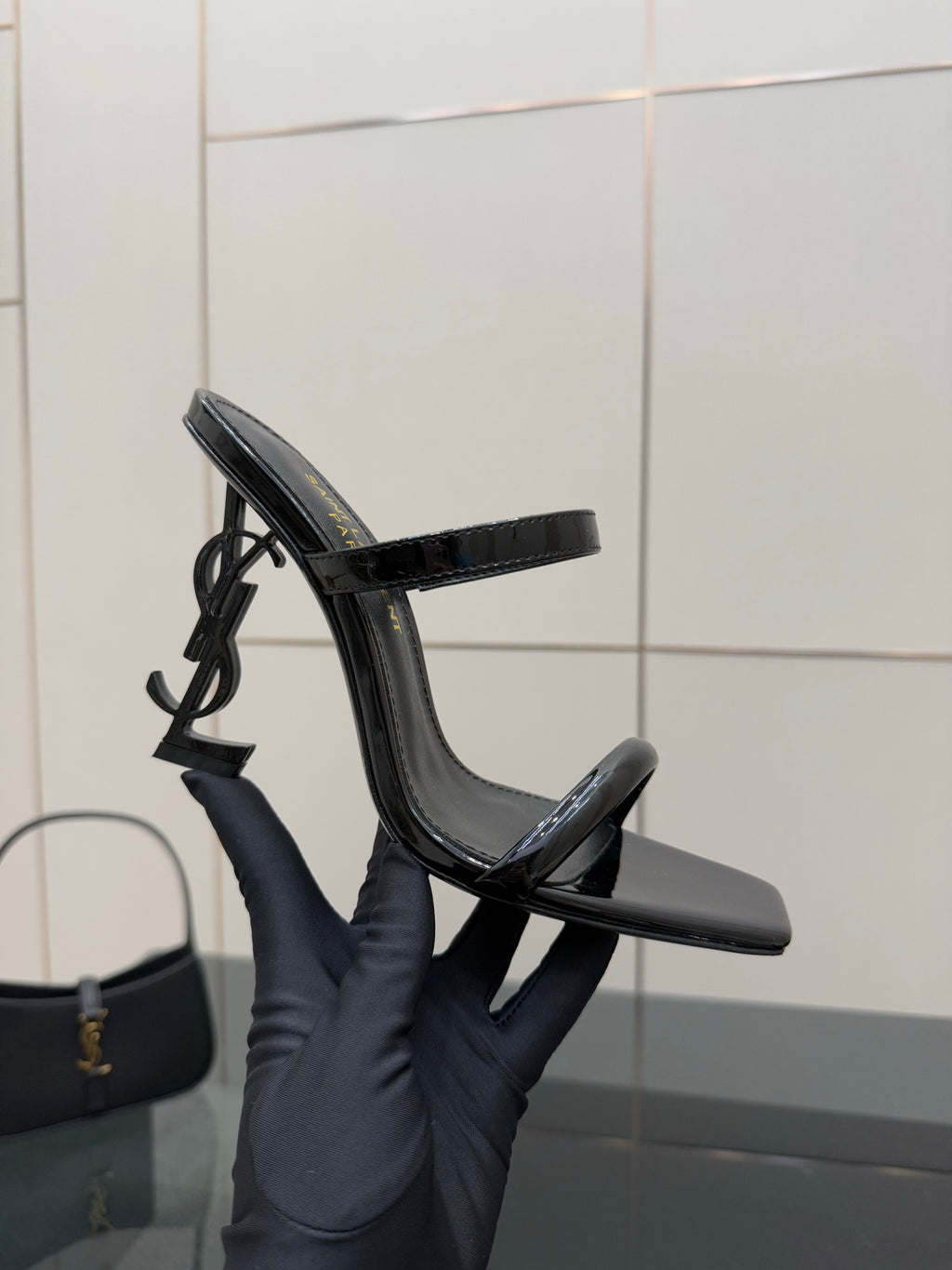 Black patent heeled mule with open toe and ankle strap, upright side angle