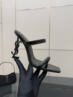 Black patent heeled mule with open toe and ankle strap, upright side angle
