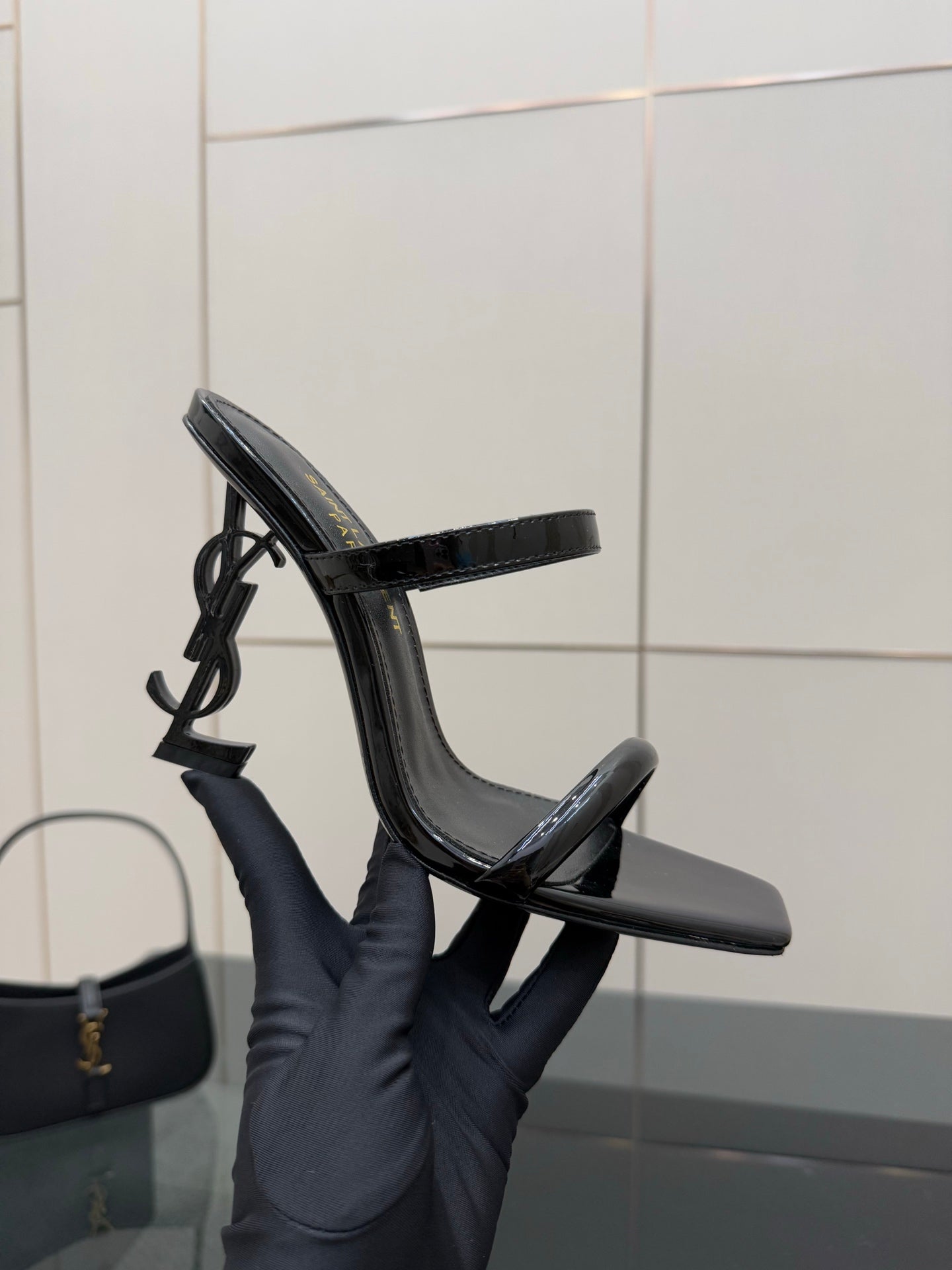Black patent heeled mule with open toe and ankle strap, upright side angle