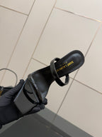 Black patent mule with open toe and ankle strap, sole and footbed visible
