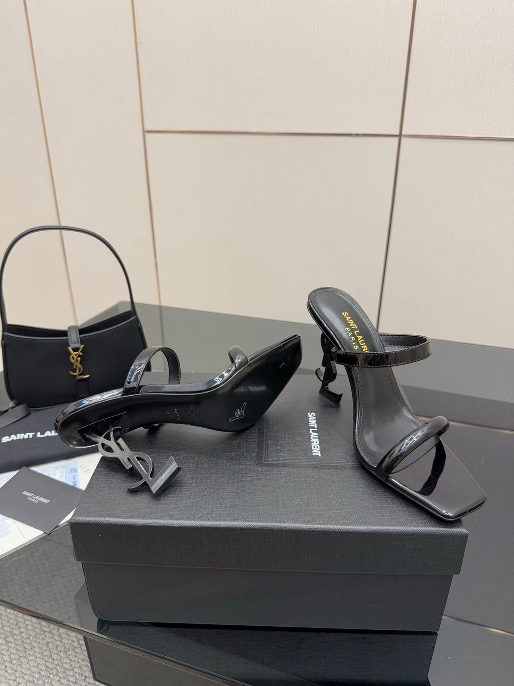 Black patent heeled mules with open toe and ankle strap, pair on shoe box