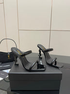 Black heeled strappy mules with open toe and slim heel, shown from side angle