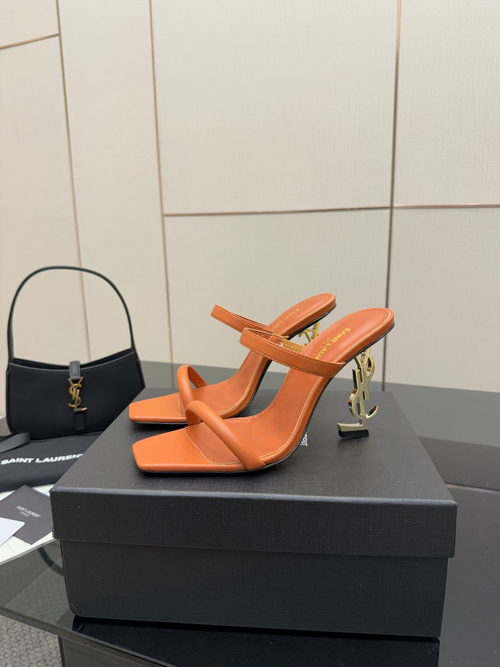 Orange YSL mule sandals with open toe and sculpted block heel, angled view.