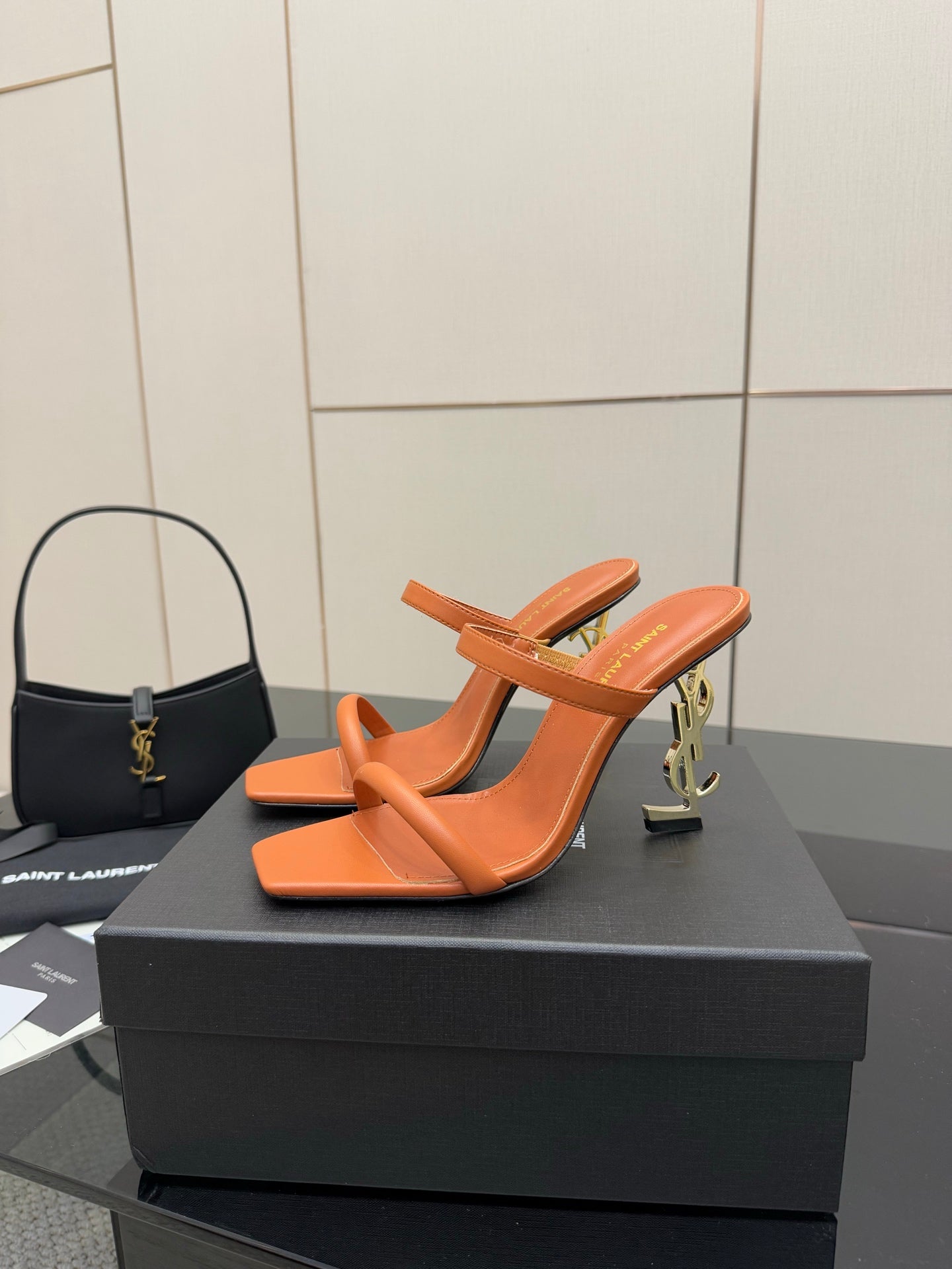 Orange YSL mule sandals with open toe and sculpted block heel, angled view.