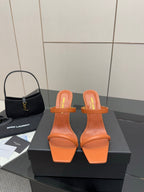 Orange YSL slide mule sandals with open toe, sculpted block heel, and gold logo detail.