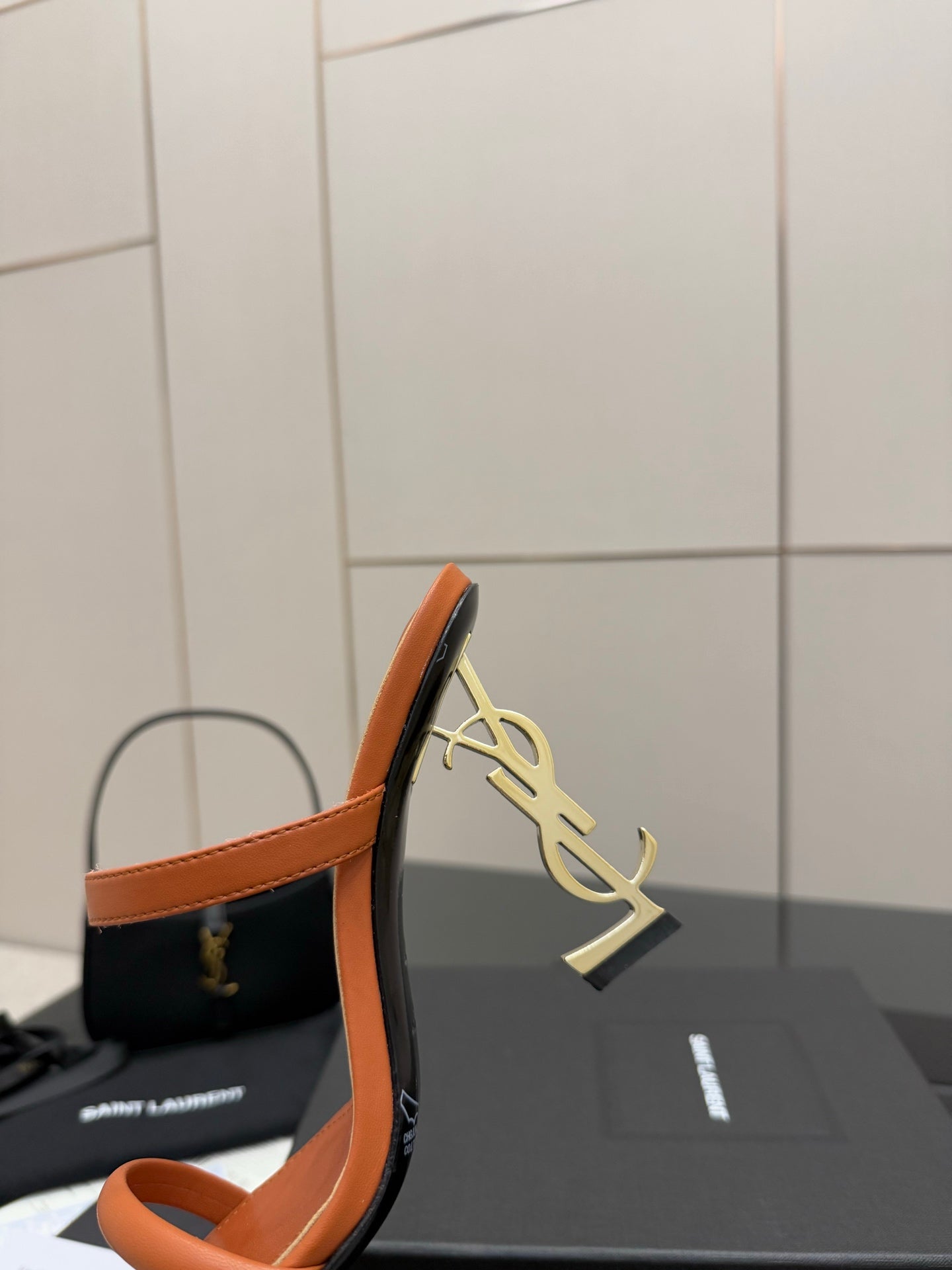 Orange YSL mule sandal with gold YSL logo on the heel and open toe.