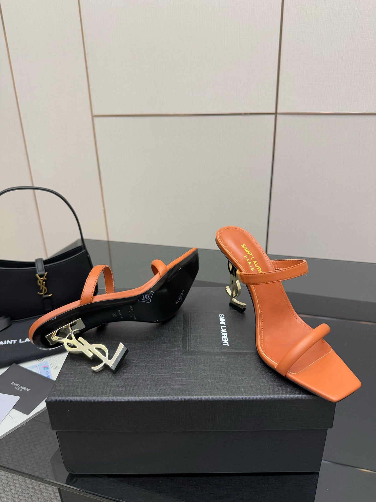 Orange and black YSL mule sandals with open toe and sculpted heels, side-by-side.