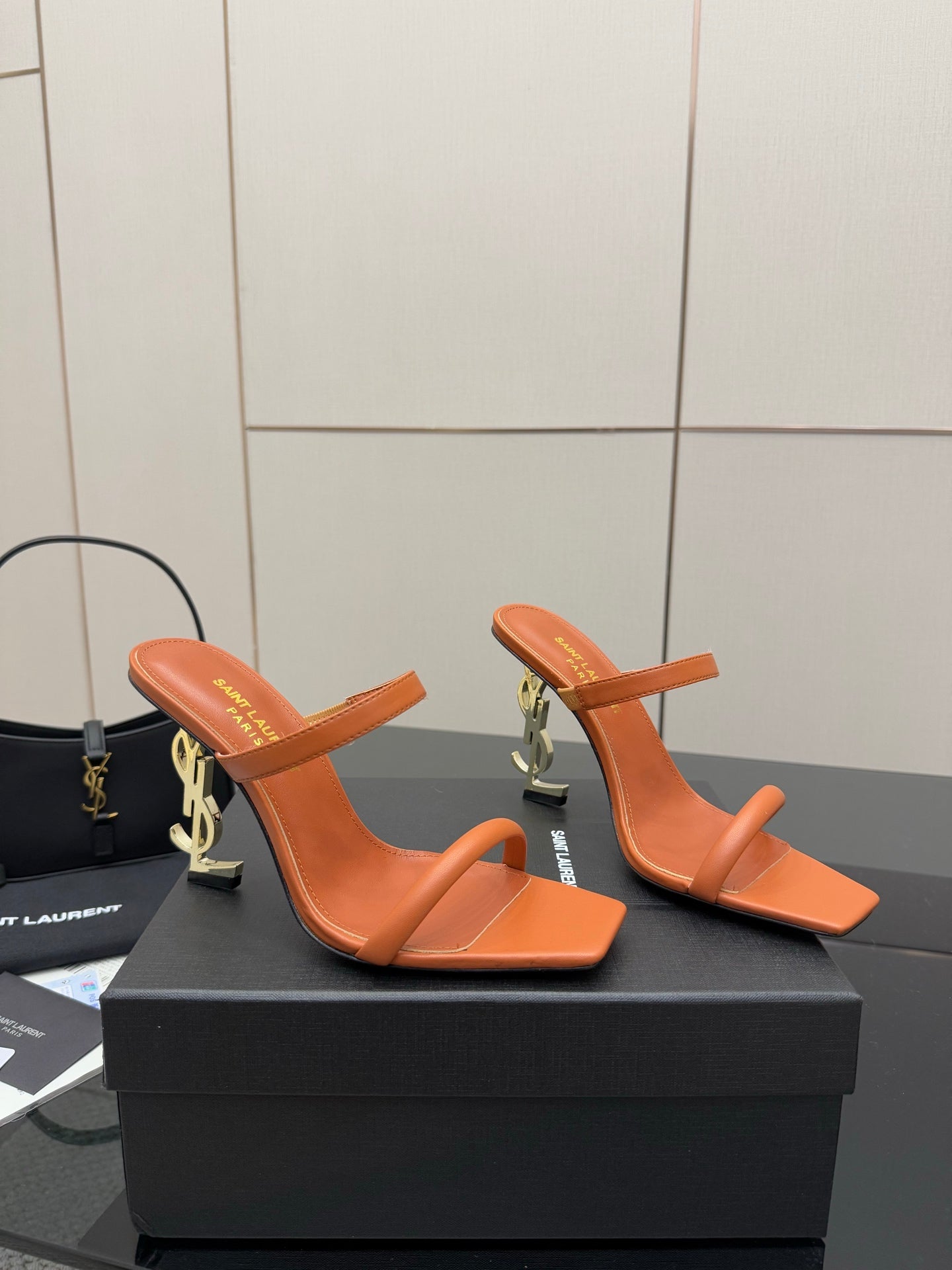 Orange YSL slide sandals with open toe and sculpted block heels, front view on box.