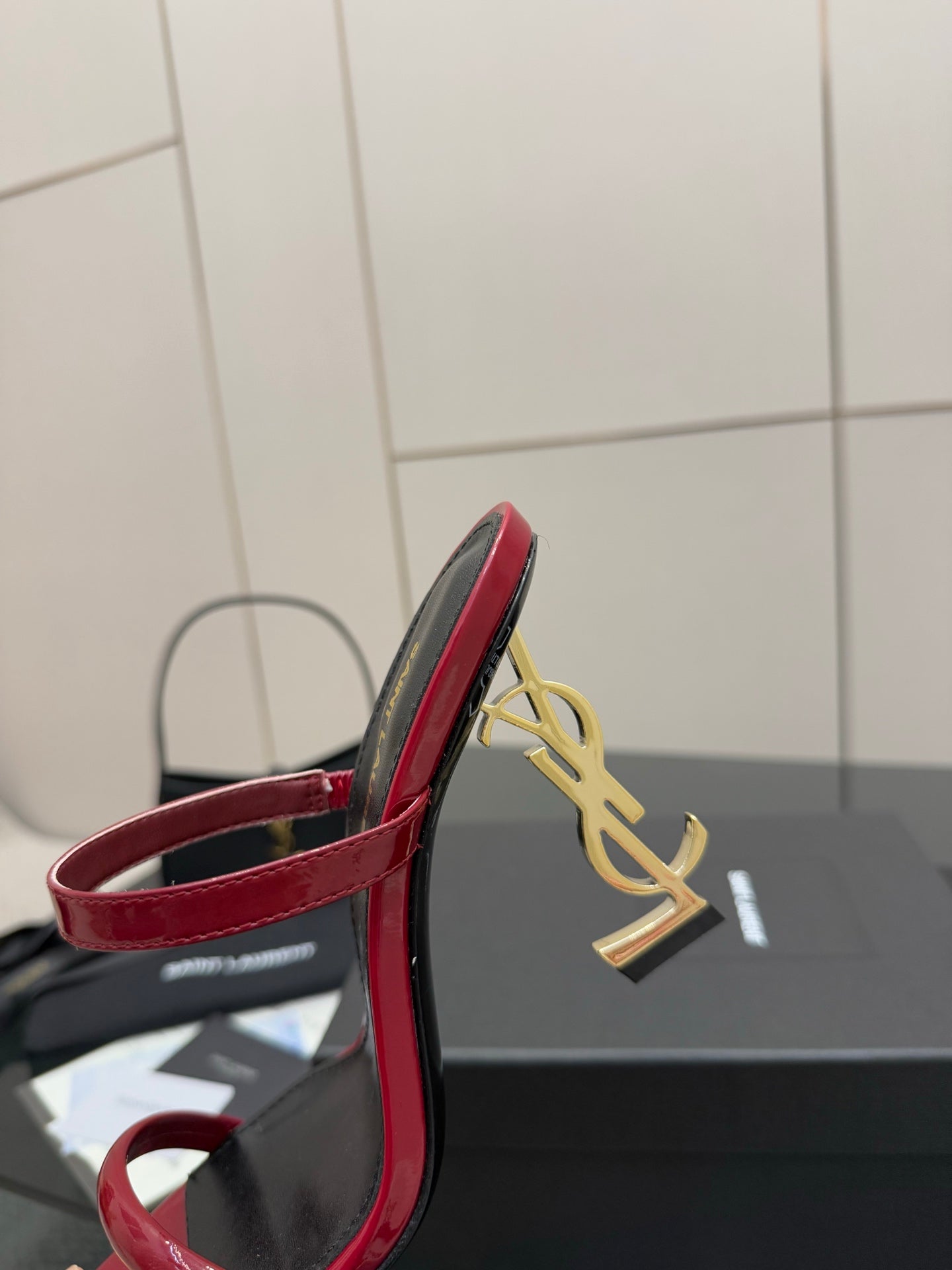 YSL ladies sandal heel close-up, gold YSL charm on black heel with red trim