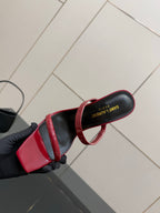 YSL ladies sandals close-up, red and black strap with gold YSL logo on sole edge