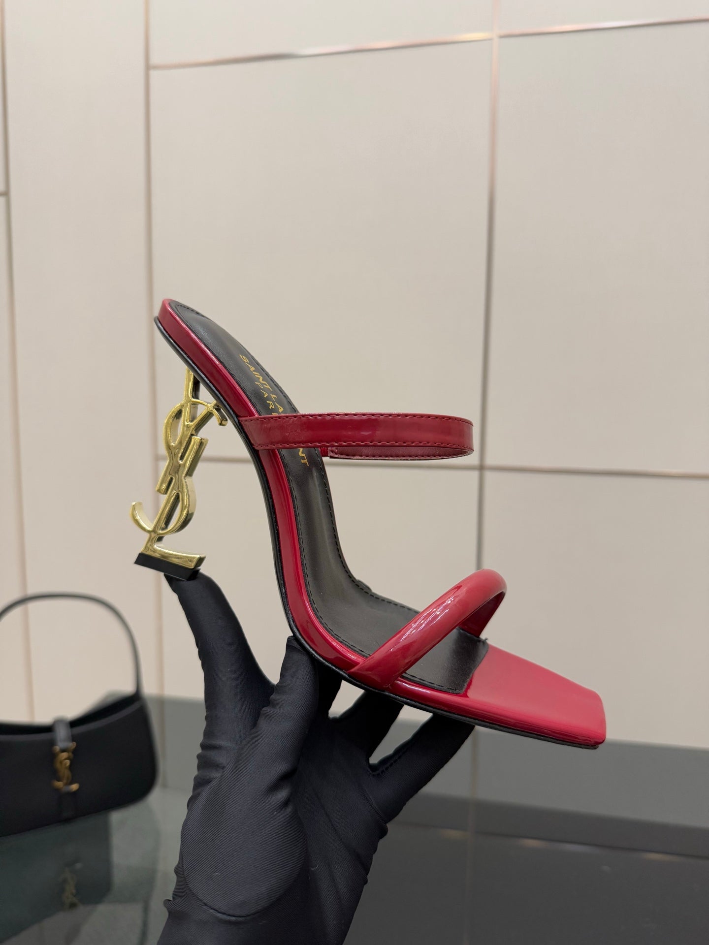 YSL ladies heeled sandal, heel detail view, gold YSL logo charm on red strap