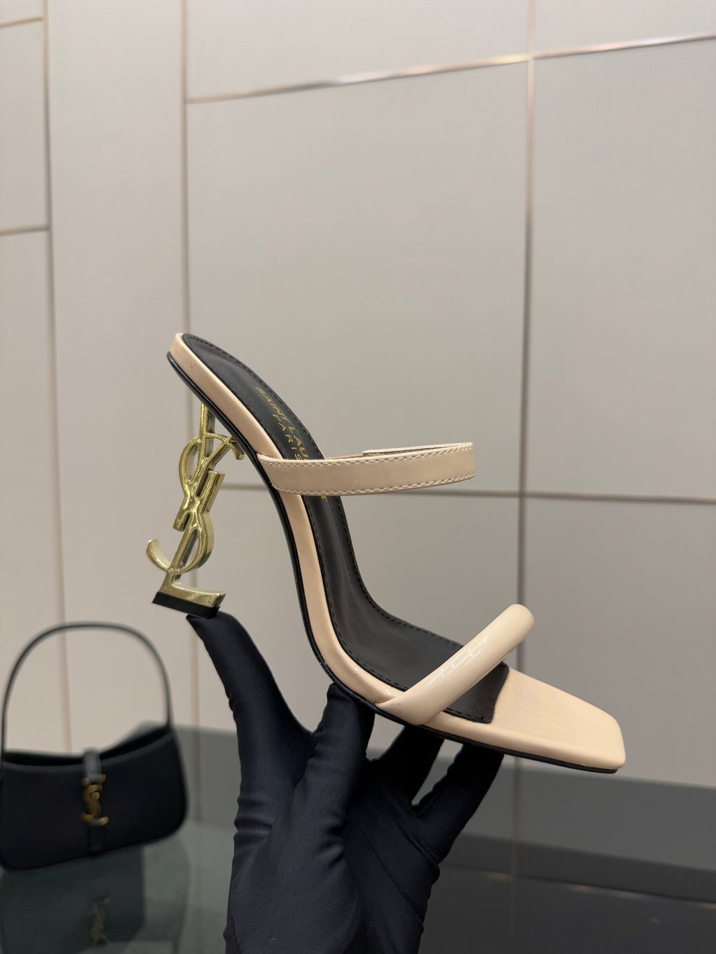 Two-tone heeled mule sandals with black lining, beige straps, and gold hardware