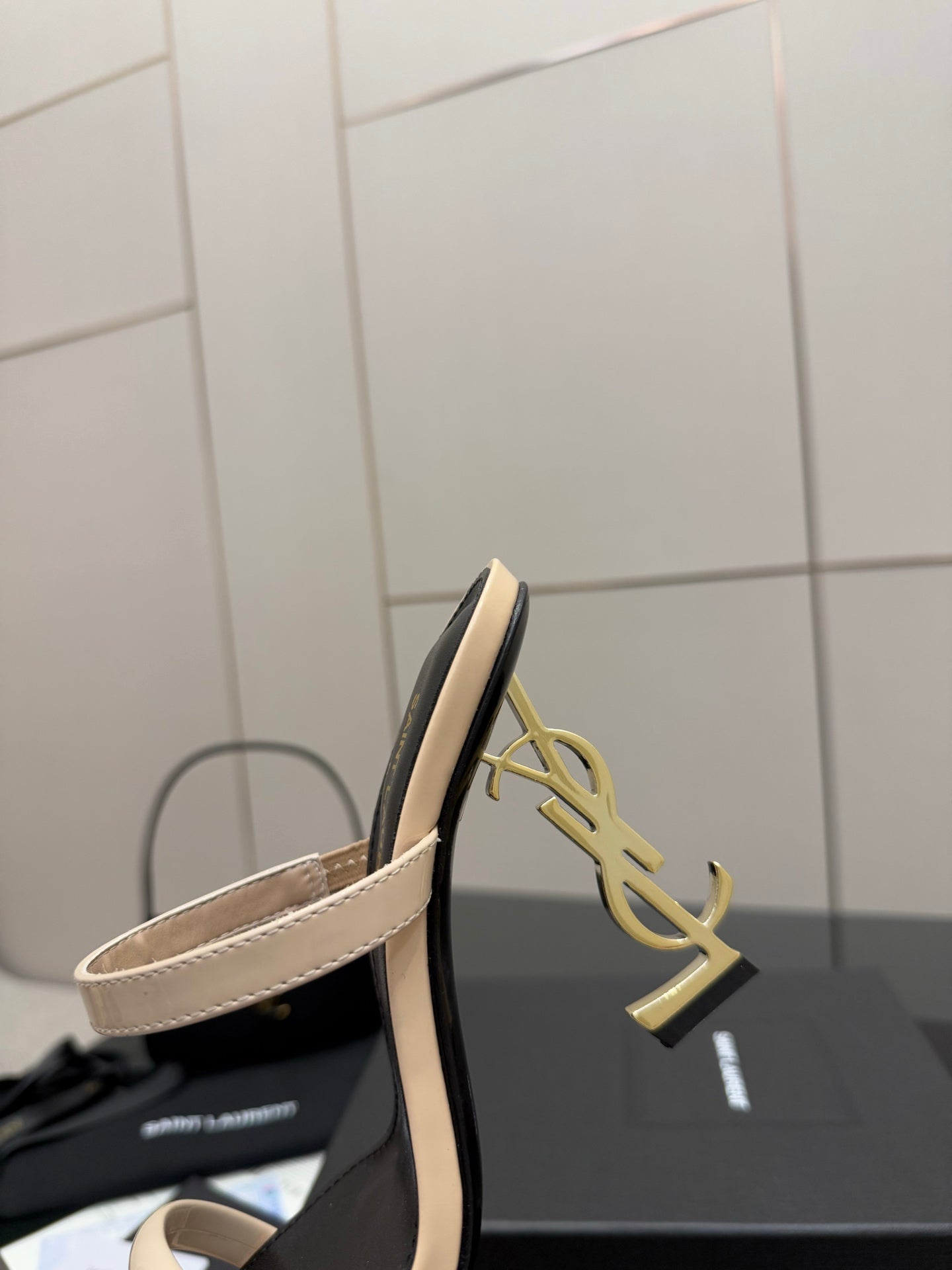 Close-up of two-tone heeled mule sandal with beige strap and black heel cap