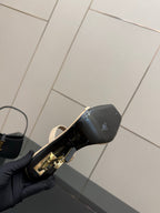 Two-tone heeled mule sandal showing black heel cap and gold logo hardware